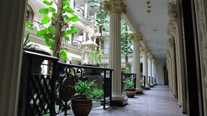 A corridor with columns and potted plants, leading to balconies with railings. - The Grand Palace Hotel Malang (Malang)