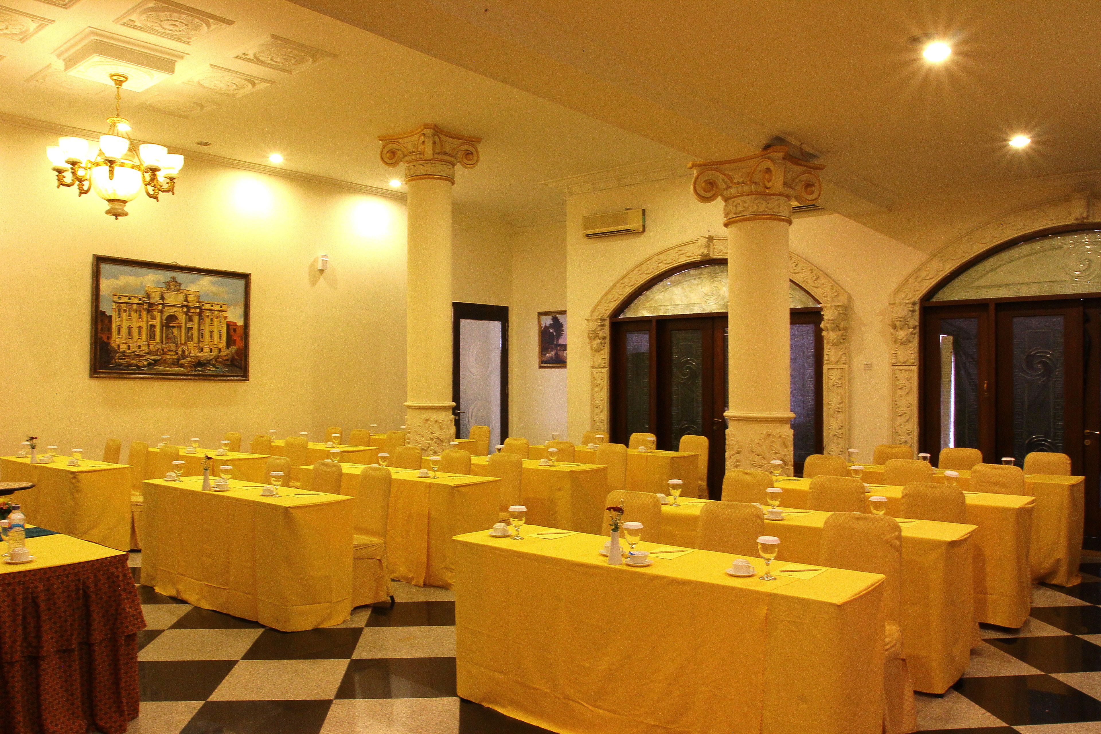 Une salle de banquet avec de nombreuses tables recouvertes de nappes jaunes, disposées en rangées.