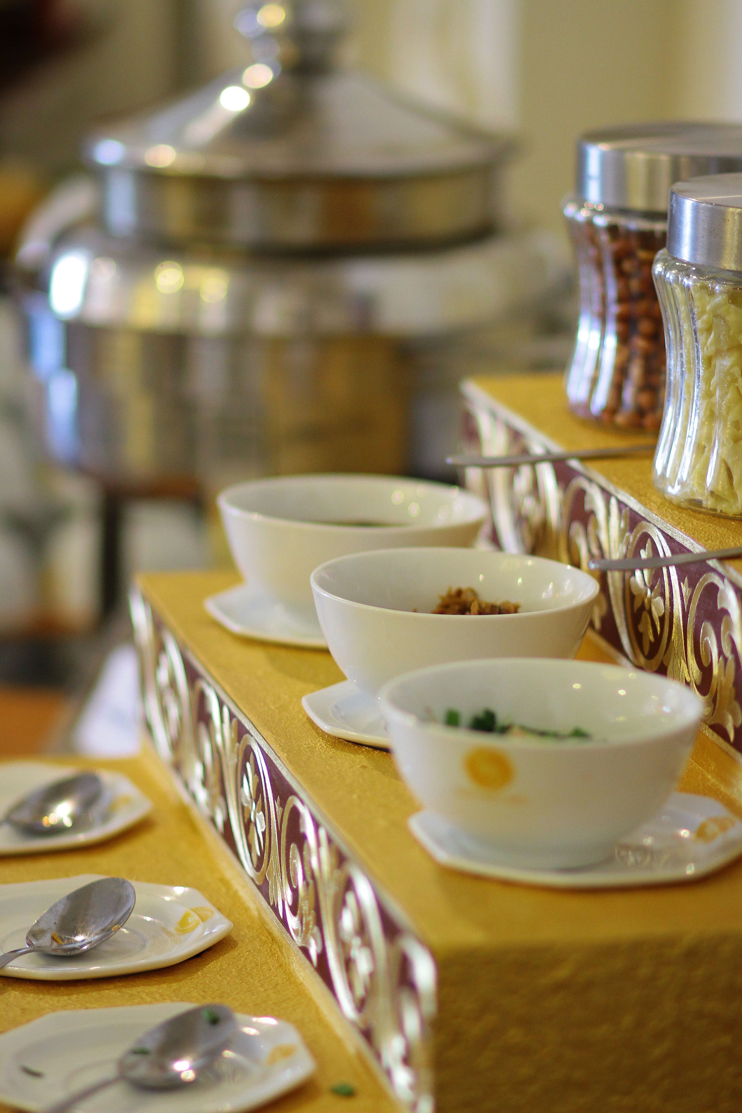 A buffet setup with multiple bowls and spoons on a table.