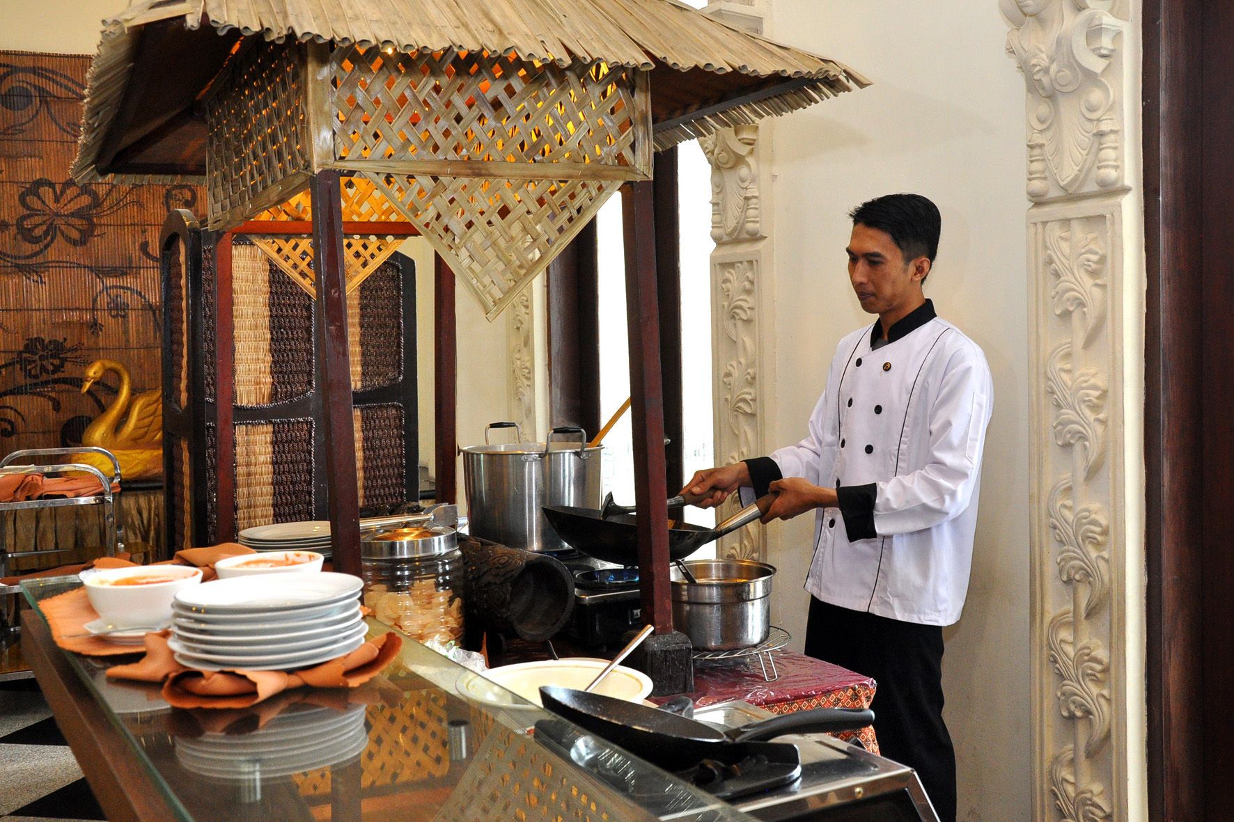 A chef preparing food in a traditional kitchen with ornate decor and a decorative canopy.
