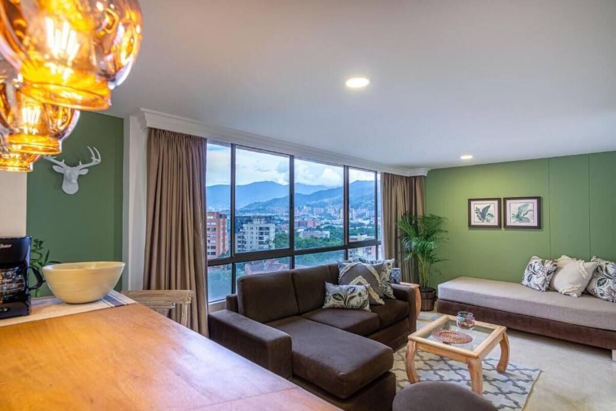 Un salon avec une grande fenêtre, un canapé, une table basse et une table à manger.