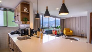 Una cocina moderna con una isla central, iluminación colgante y vistas de la ciudad.