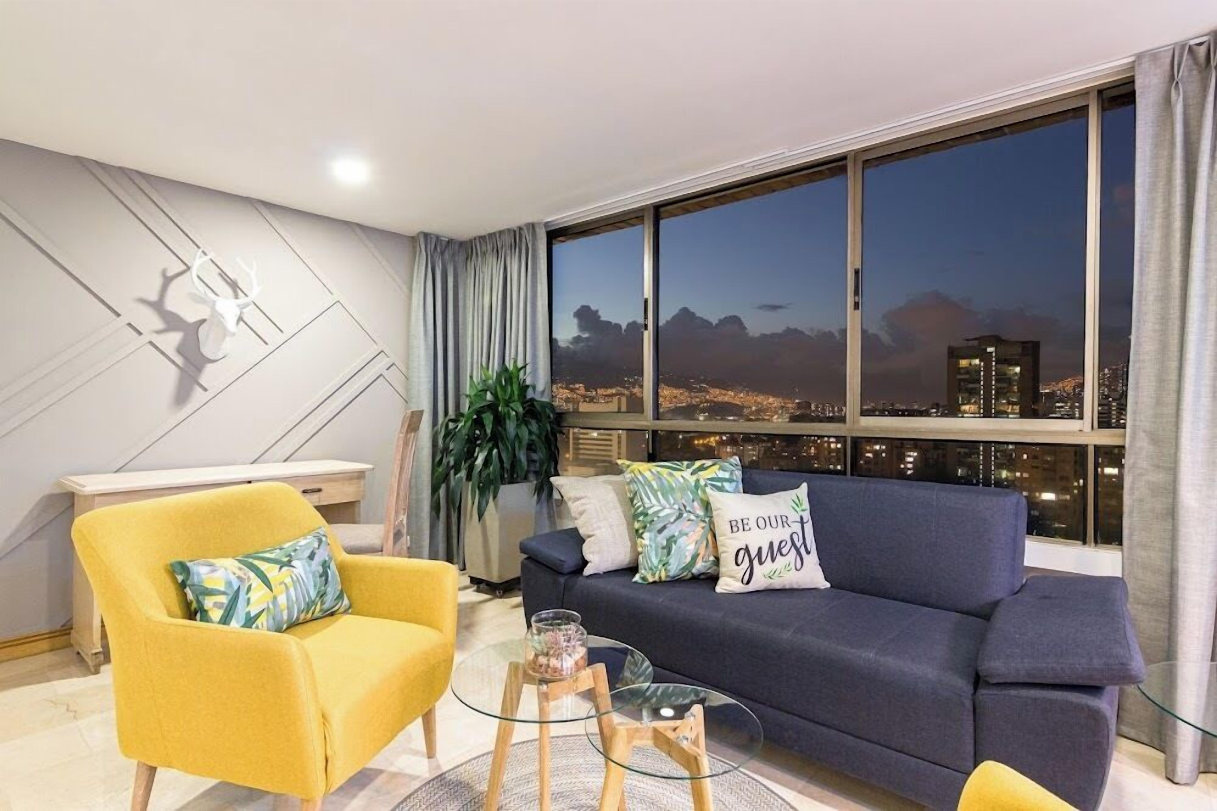 A modern living room with a sofa, armchair, and a glass coffee table.