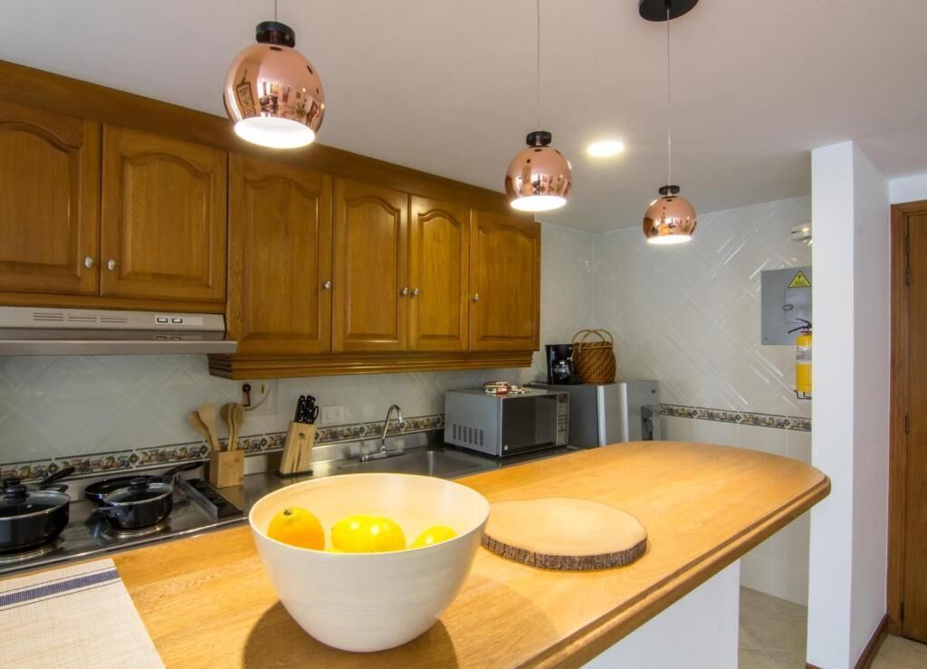 A kitchen with wooden cabinets, a microwave, a toaster, and a bowl of lemons on the counter.