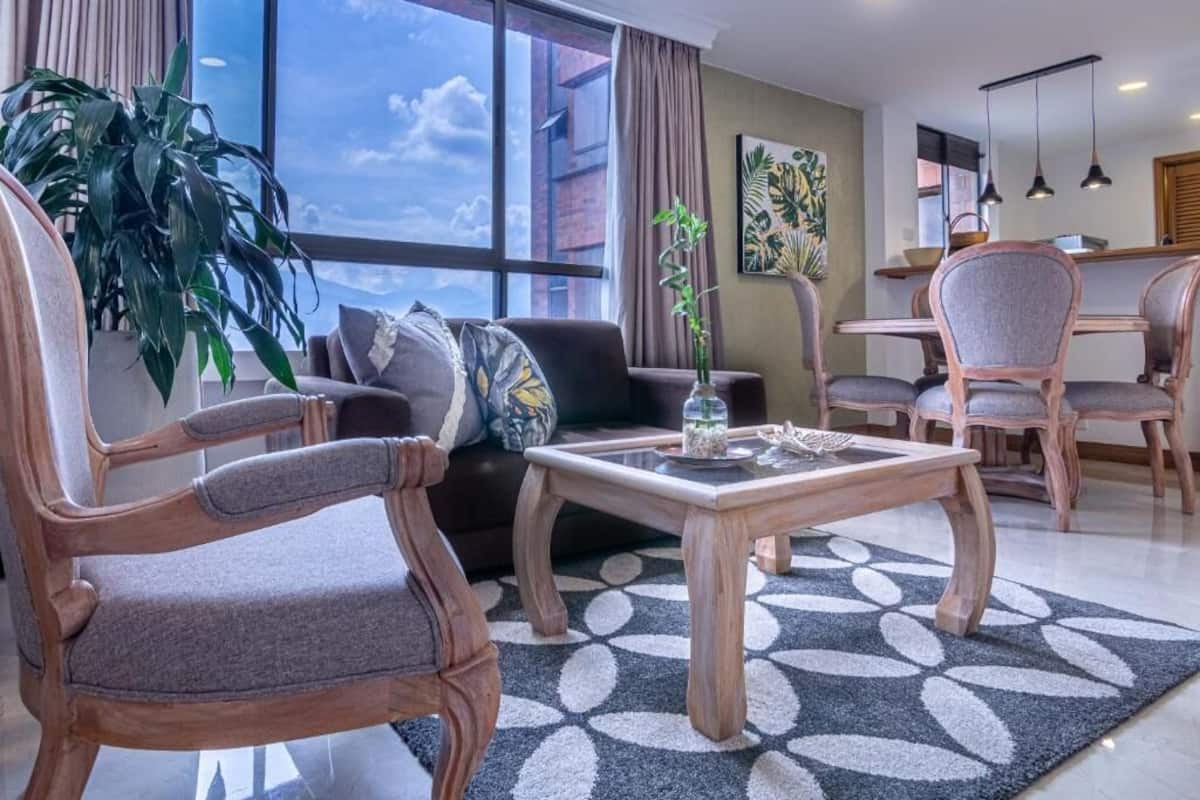 Un salon moderne comprenant un canapé, deux fauteuils, une table basse et un coin repas avec des chaises et une table.