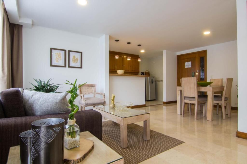 Una sala de estar moderna con un sofá, una mesa de centro y un comedor con una mesa y sillas.