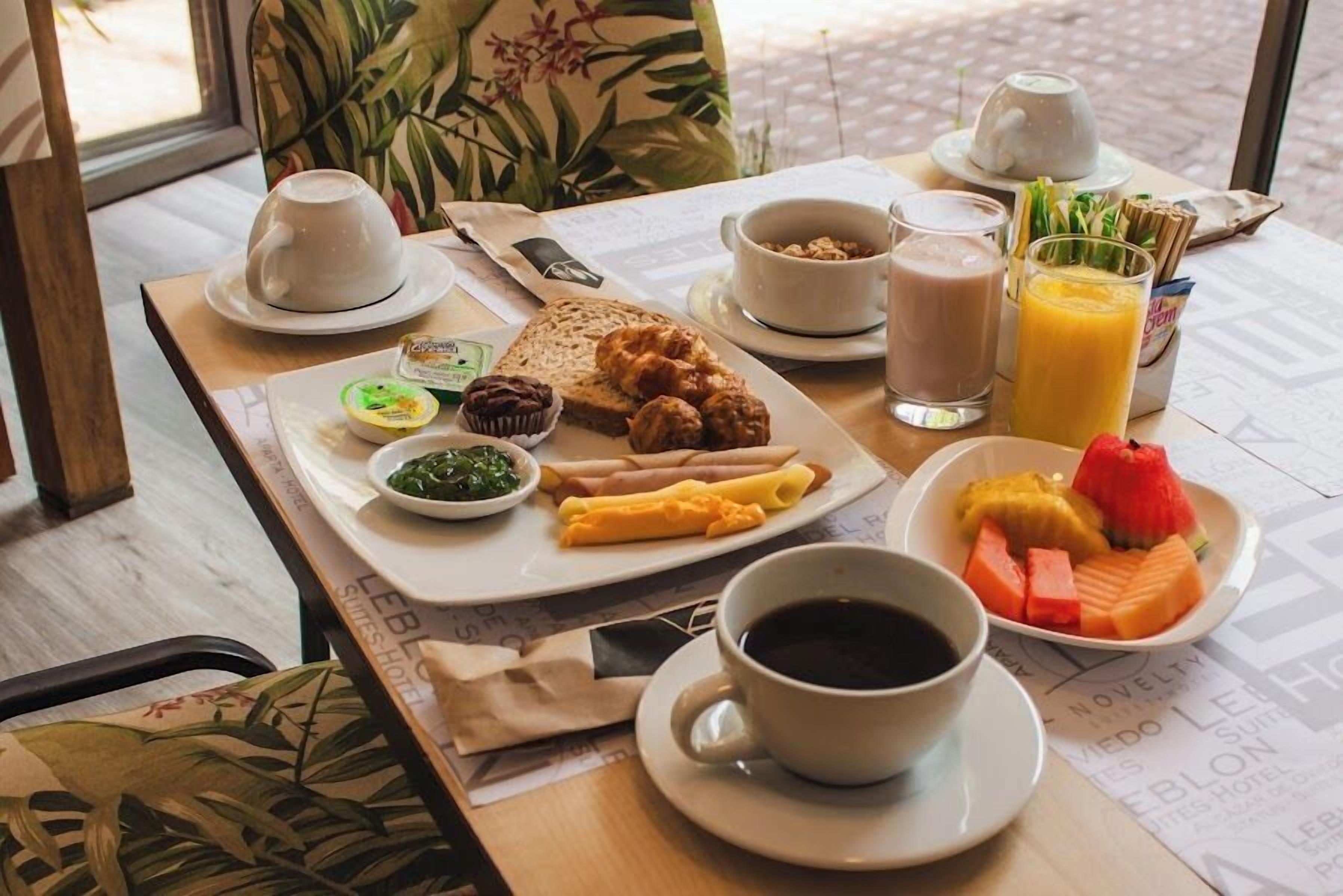 A breakfast table with a variety of food items, including pastries, fruits, and beverages.