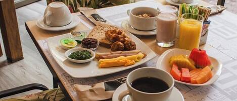 A breakfast table with a variety of food items, including pastries, fruits, and beverages.