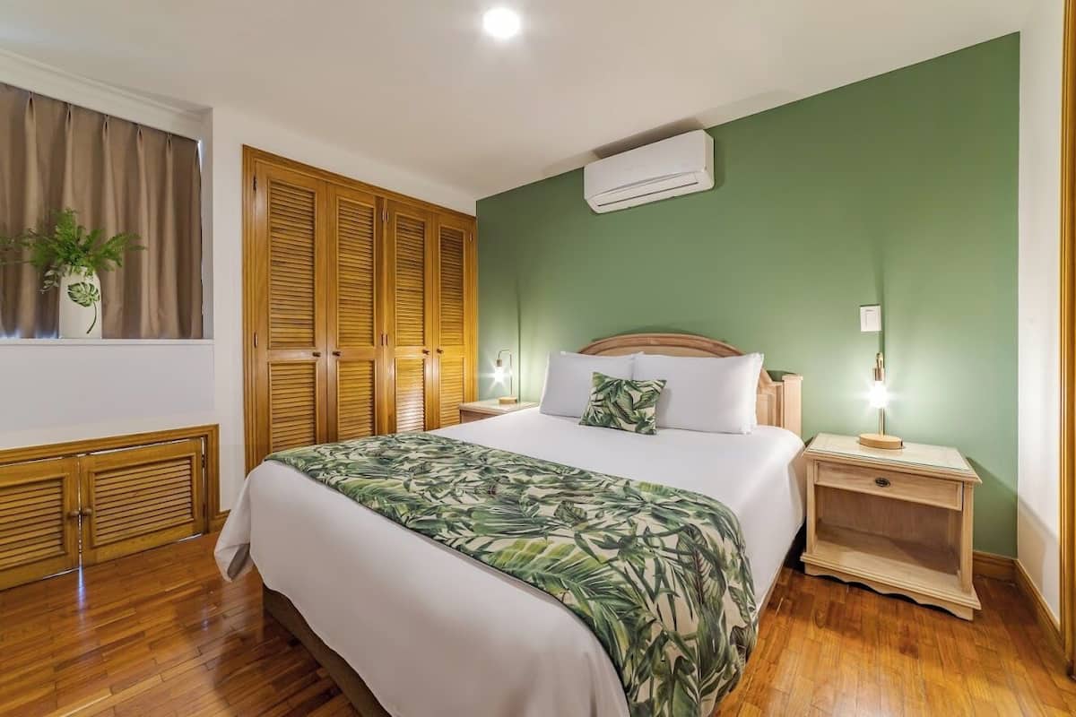 Une chambre à coucher avec un lit, une armoire en bois et un appareil de climatisation.