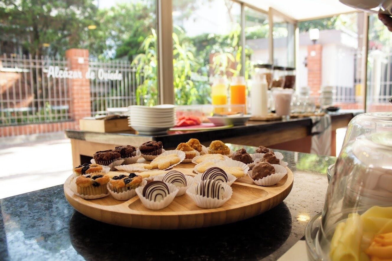 A breakfast buffet with various pastries and a glass of orange juice on a wooden board.
