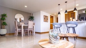 Un comedor moderno con una mesa redonda de madera, dos sillas azules y un jarrón con flores.