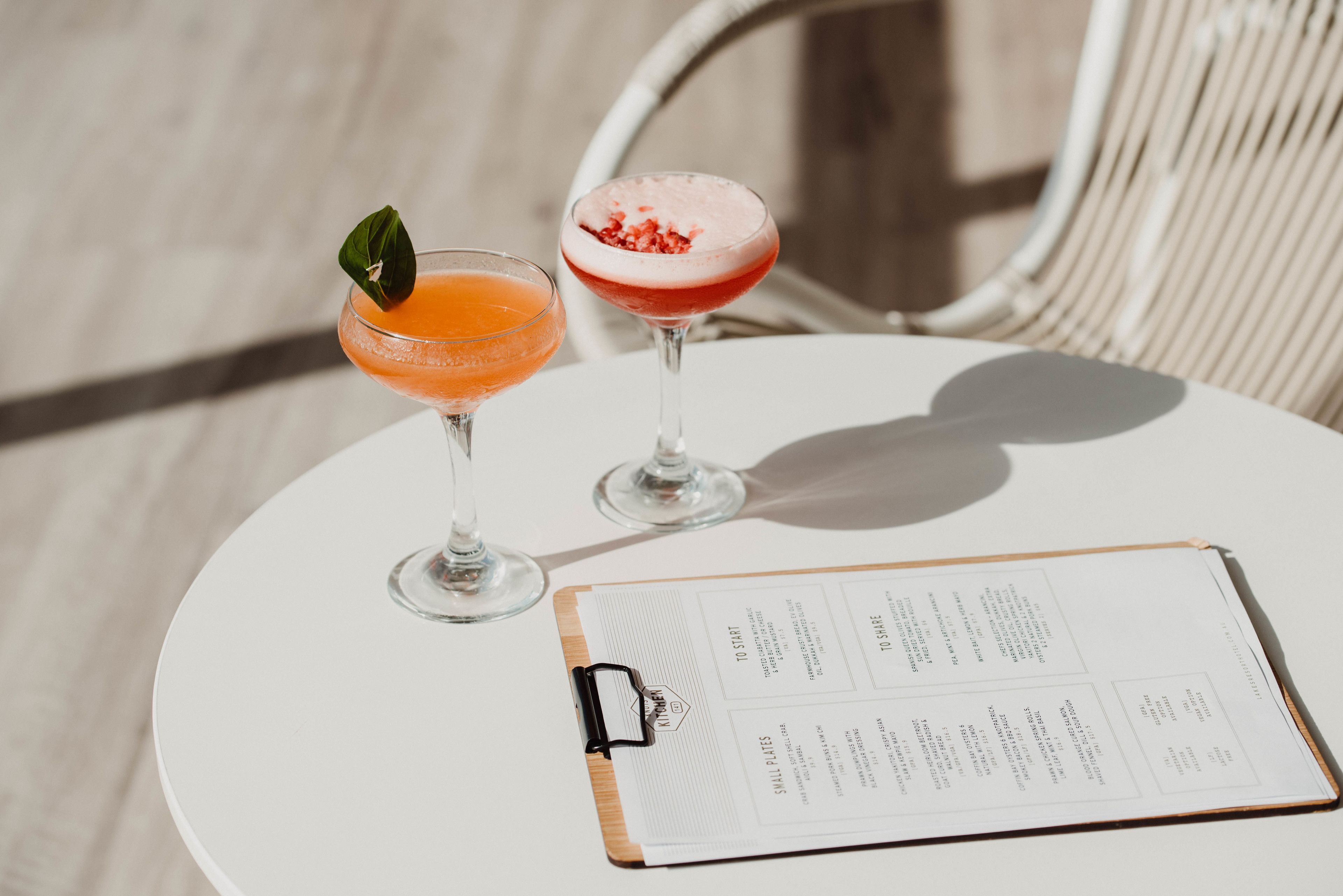 Two drinks on a white table with a menu.