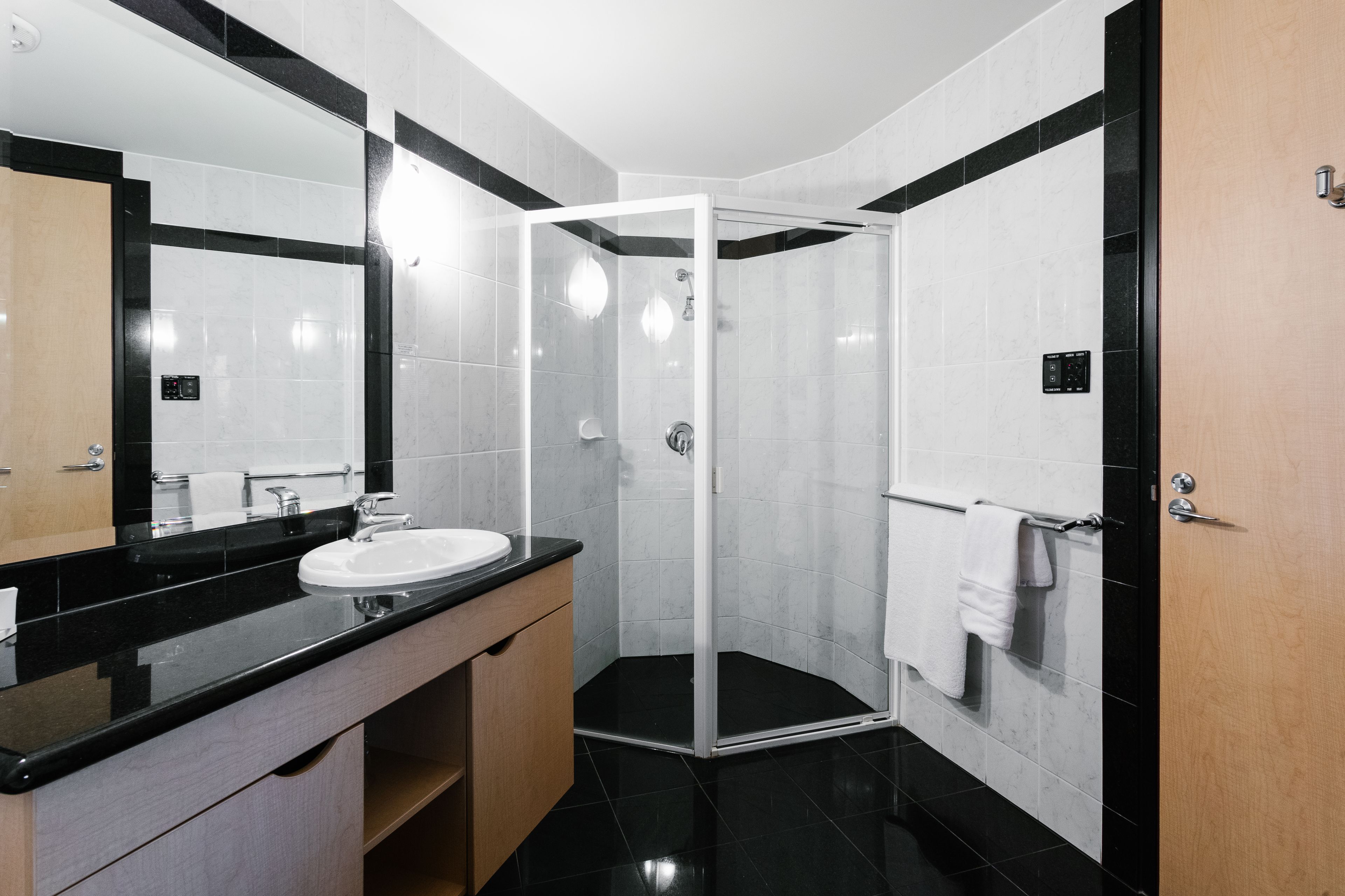 A modern bathroom with a glass-enclosed shower, a white sink, and a black countertop.