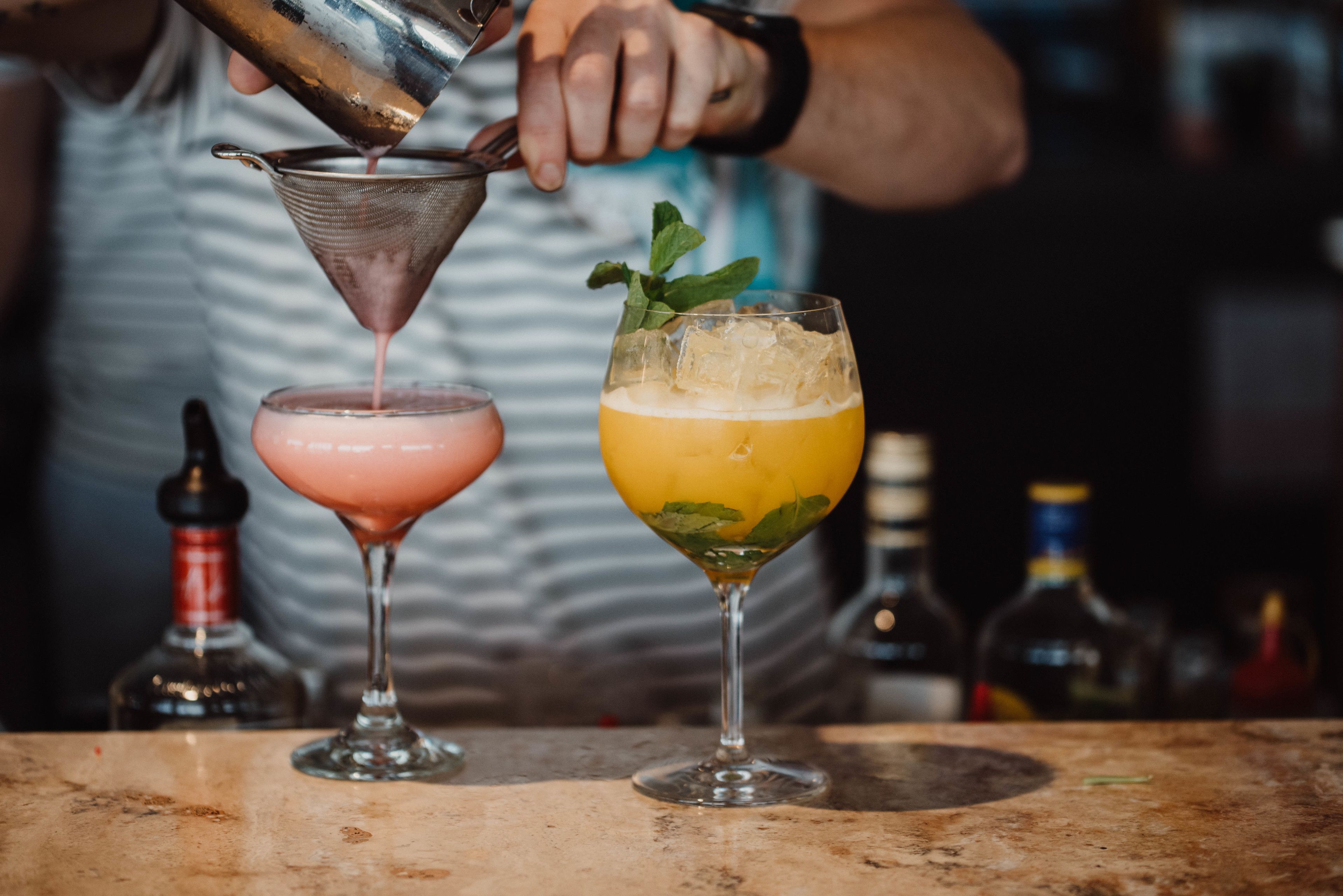 A bartender pouring a drink into a glass.