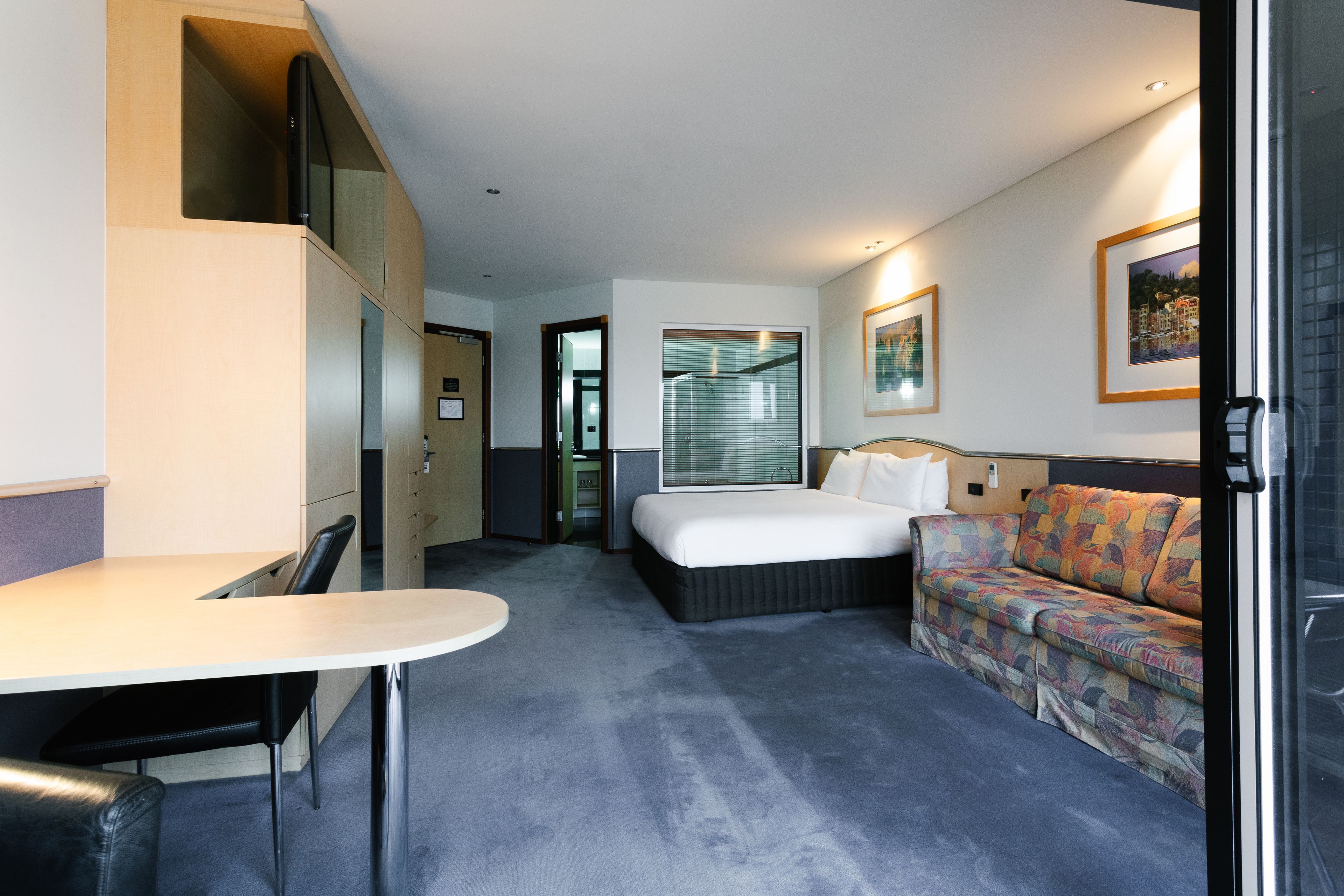 A hotel room with a bed, a sofa, a desk, and a chair.