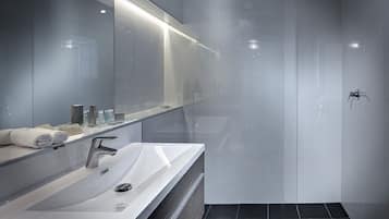 A modern bathroom with a large mirror, a sink, and a shower area.