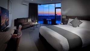 A modern hotel room with a large bed, a sofa, a desk, and a TV. - Lakes Hotel (West Lakes)