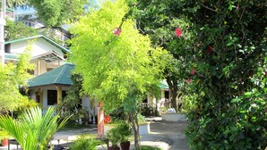 A pathway lined with potted plants and a building with a green roof. - Seashore Beach Resort (Puerto Galera)