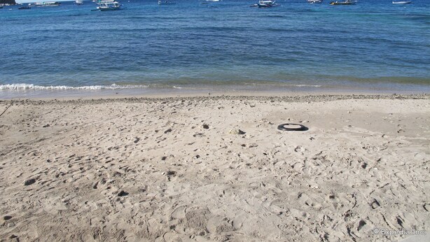A beach with footprints and a tire on the sand, boats in the water, and a mountain in the background. - Seashore Beach Resort (Puerto Galera)