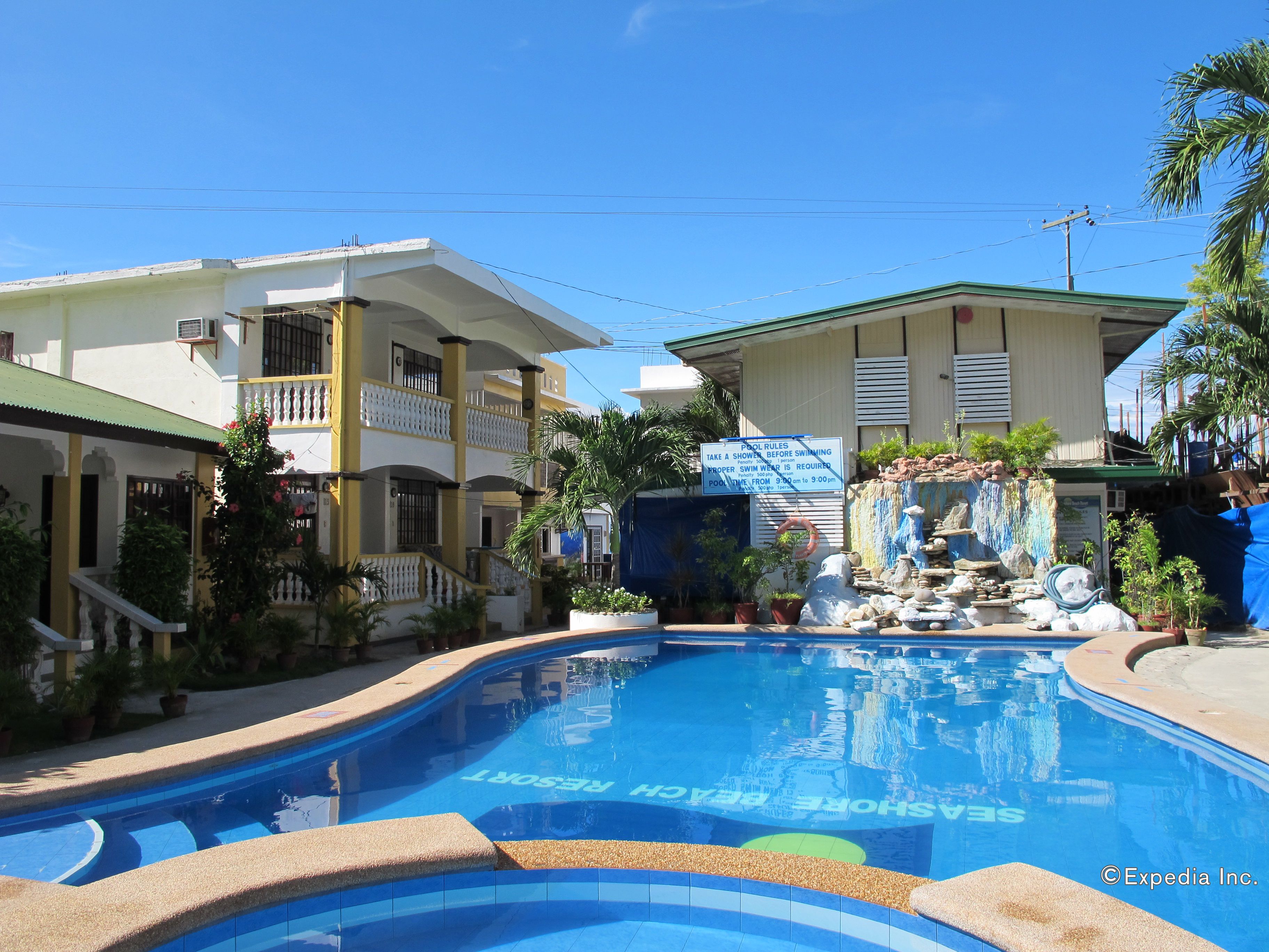 A swimming pool with a sign indicating pool rules and a resort name.