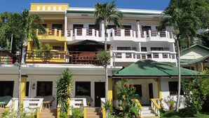 A multi-story hotel with a pool area, balconies, and tropical landscaping. - Seashore Beach Resort (Puerto Galera)