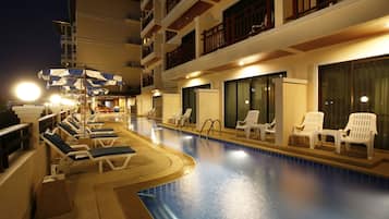 Una piscina al aire libre, sombrillas, sillones reclinables de piscina