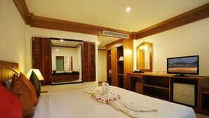 A hotel room with a bed, a TV, a mirror, and a wooden wardrobe. - Jiraporn Hill Resort (Patong)