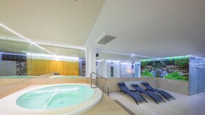 Un moderno espacio de spa con hidromasaje, sillones reclinables y un mural de una cascada.