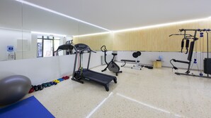 Un gimnasio con cintas de correr, elípticas, pesas libres y pelotas de ejercicio.