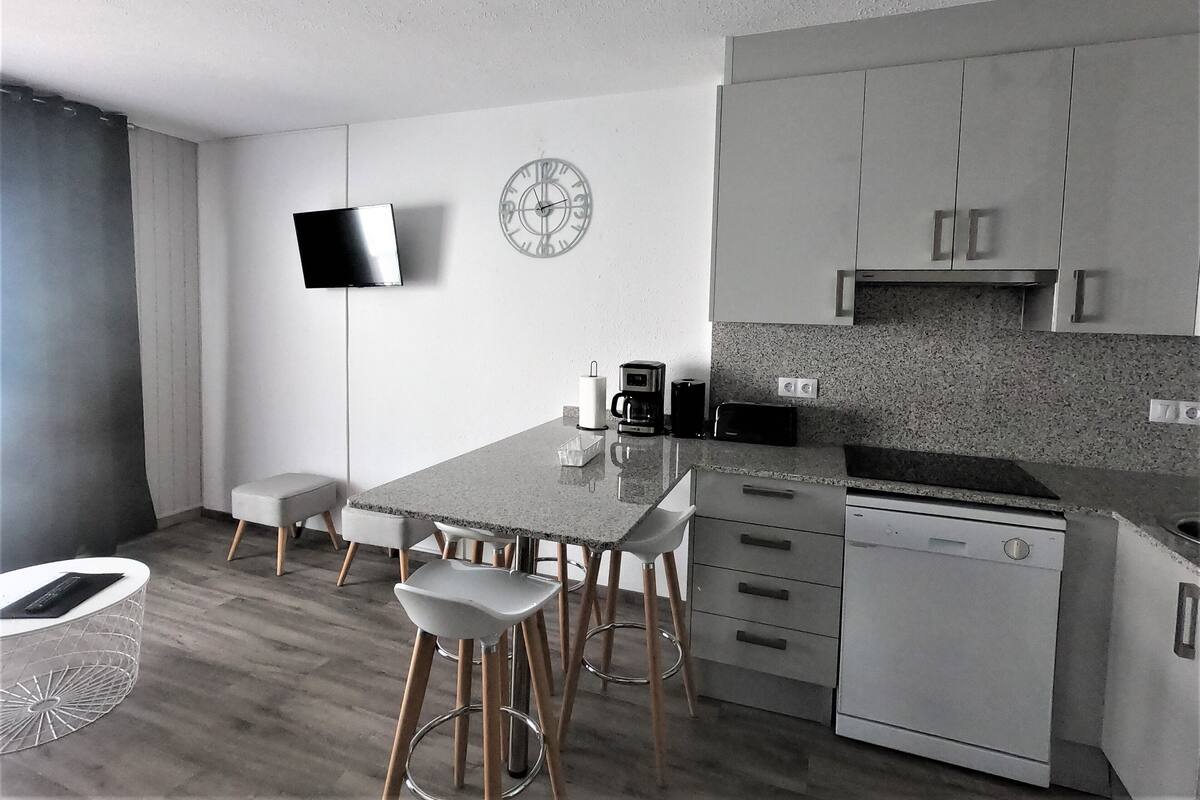 Una cocina moderna con televisor de pantalla plana, un reloj y una cafetera.