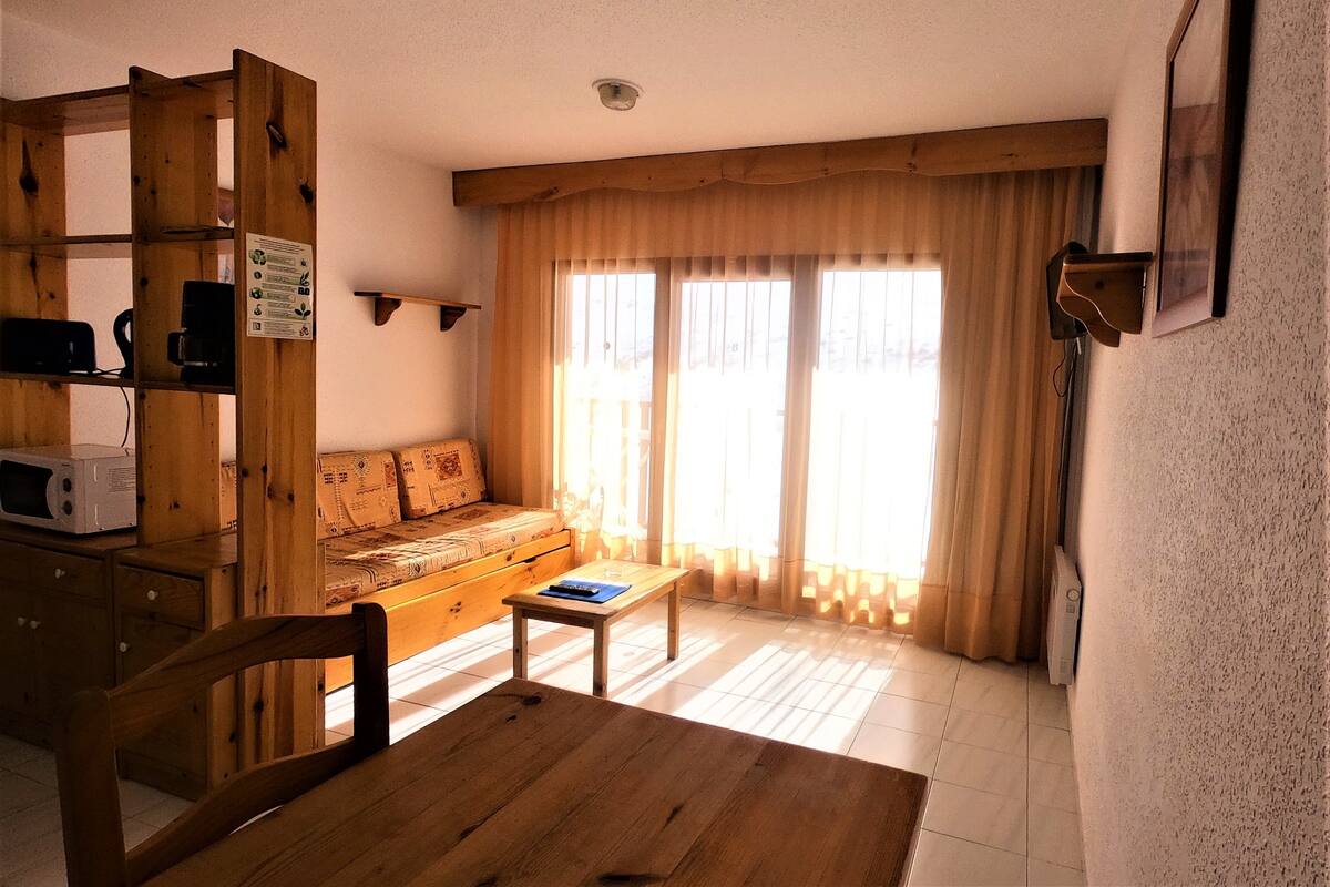 Una sala acogedora con un sofá de madera, una mesa de centro y un mueble de madera con microondas.