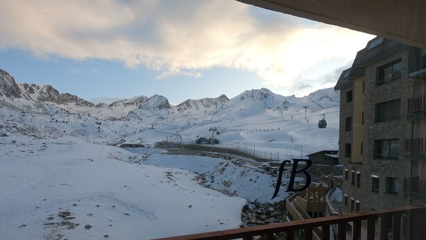 Un paysage de montagne enneigé avec un télésiège, un bâtiment en pierre et une clôture en bois.