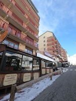A multi-story building with balconies, a restaurant, and a rental sign.