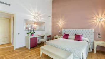 Une chambre avec un grand lit, une table de chevet, un bureau avec une chaise, un banc et un miroir au mur.