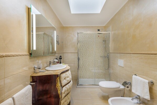 A modern bathroom with a vanity, sink, mirror, toilet, bidet, and shower.