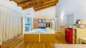 A modern bathroom with a wooden ceiling, a large bathtub, and a red refrigerator.