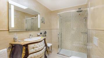 A bathroom with a glass-enclosed shower, a vanity with a mirror, and a toilet.