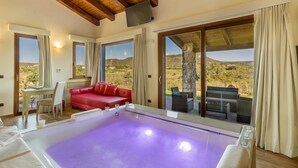 A room with a large purple heated pool, a red sofa, and a dining area with a table and chairs.