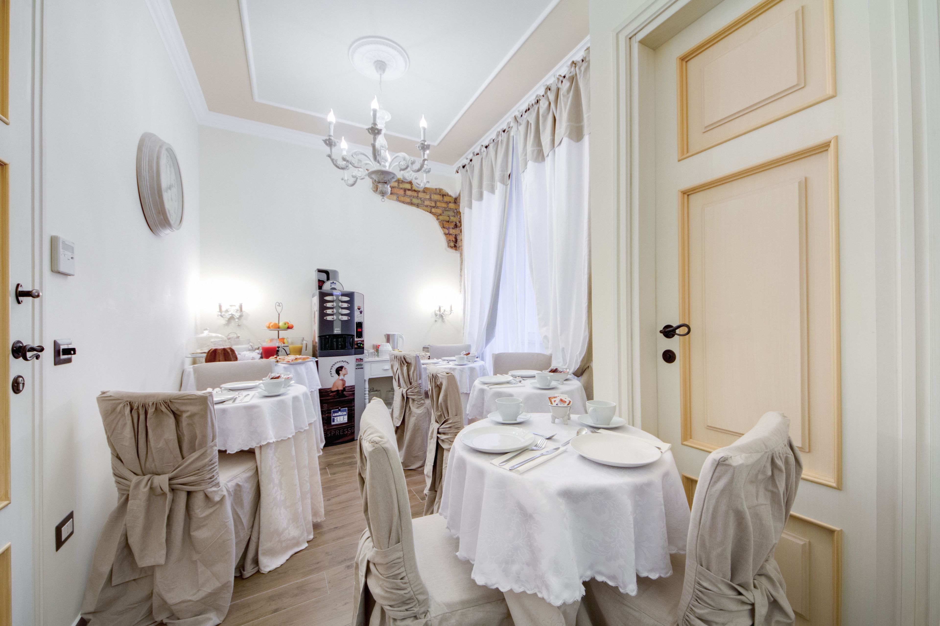 Una sala da pranzo con tavoli rotondi, sedie e un lampadario.