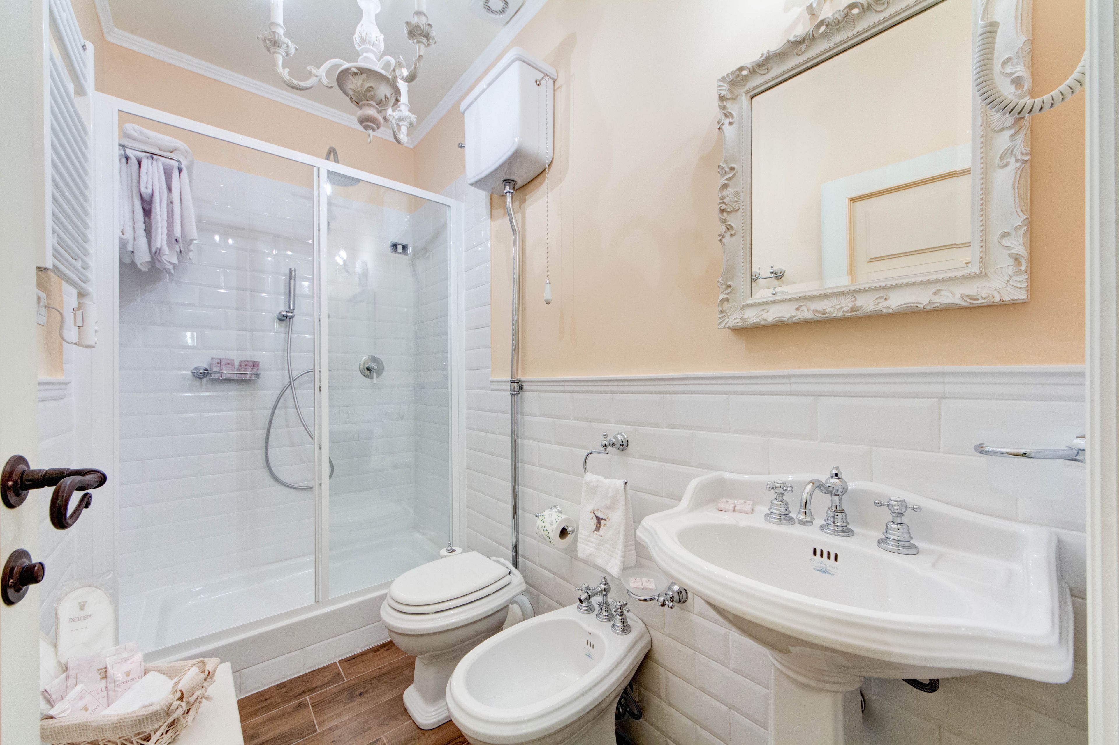 A bathroom with a glass-enclosed shower, a toilet, a bidet, and a sink.