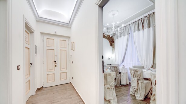 A hallway with wooden flooring, white walls, and a door with a light switch. - Lunaria Suites Rome (Rome)
