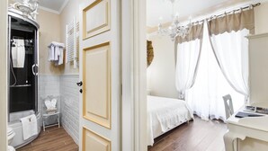 A hotel room with a bathroom, a bed, a desk, and a chandelier. - Lunaria Suites Rome (Rome)