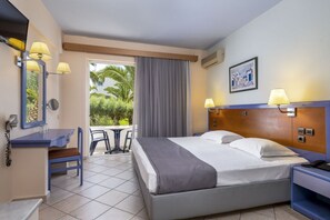 Habitación de hotel con cama, escritorio, silla, teléfono y ventana con vistas a zonas verdes.