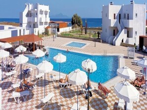 Een buitenzwembad, parasols bij het zwembad en ligstoelen