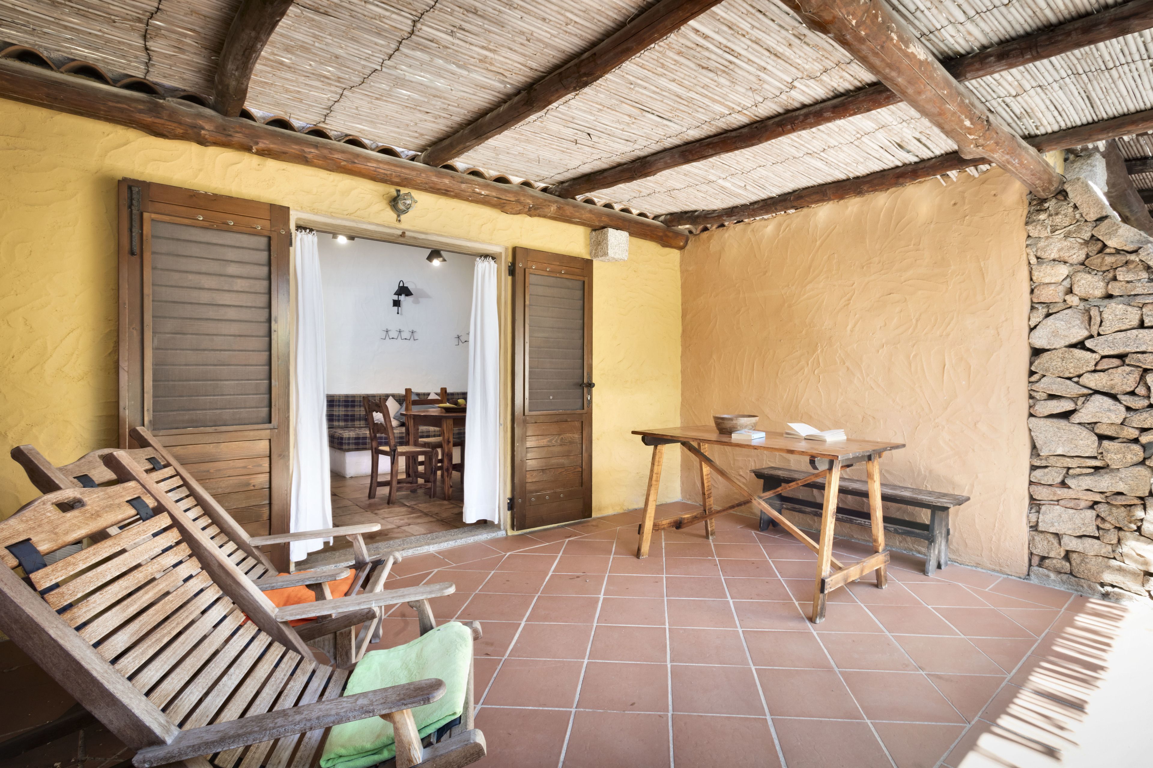 Un espace extérieur aménagé dans un style rustique, avec des meubles en bois, un mur en pierre et un toit de chaume.
