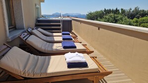A rooftop lounge area with sunbeds and a view of the sea. - Residenza Capriccioli (Arzachena)