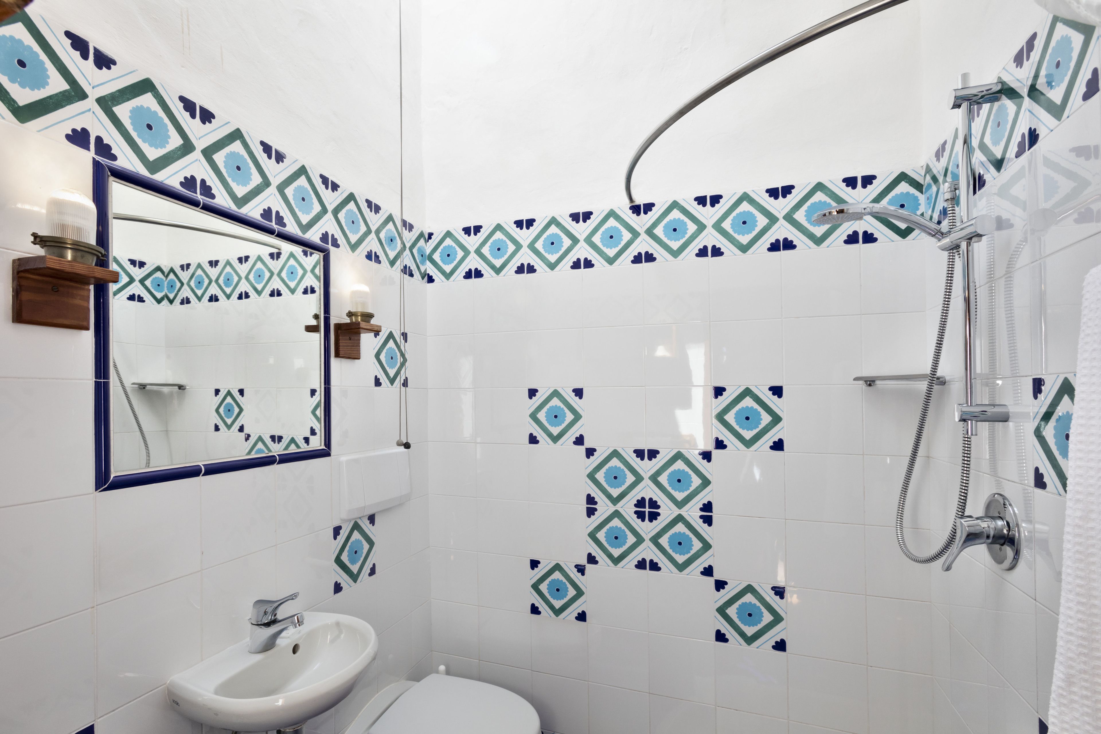 Un baño con lavamanos blanco, inodoro y ducha con cabezal de ducha manual.