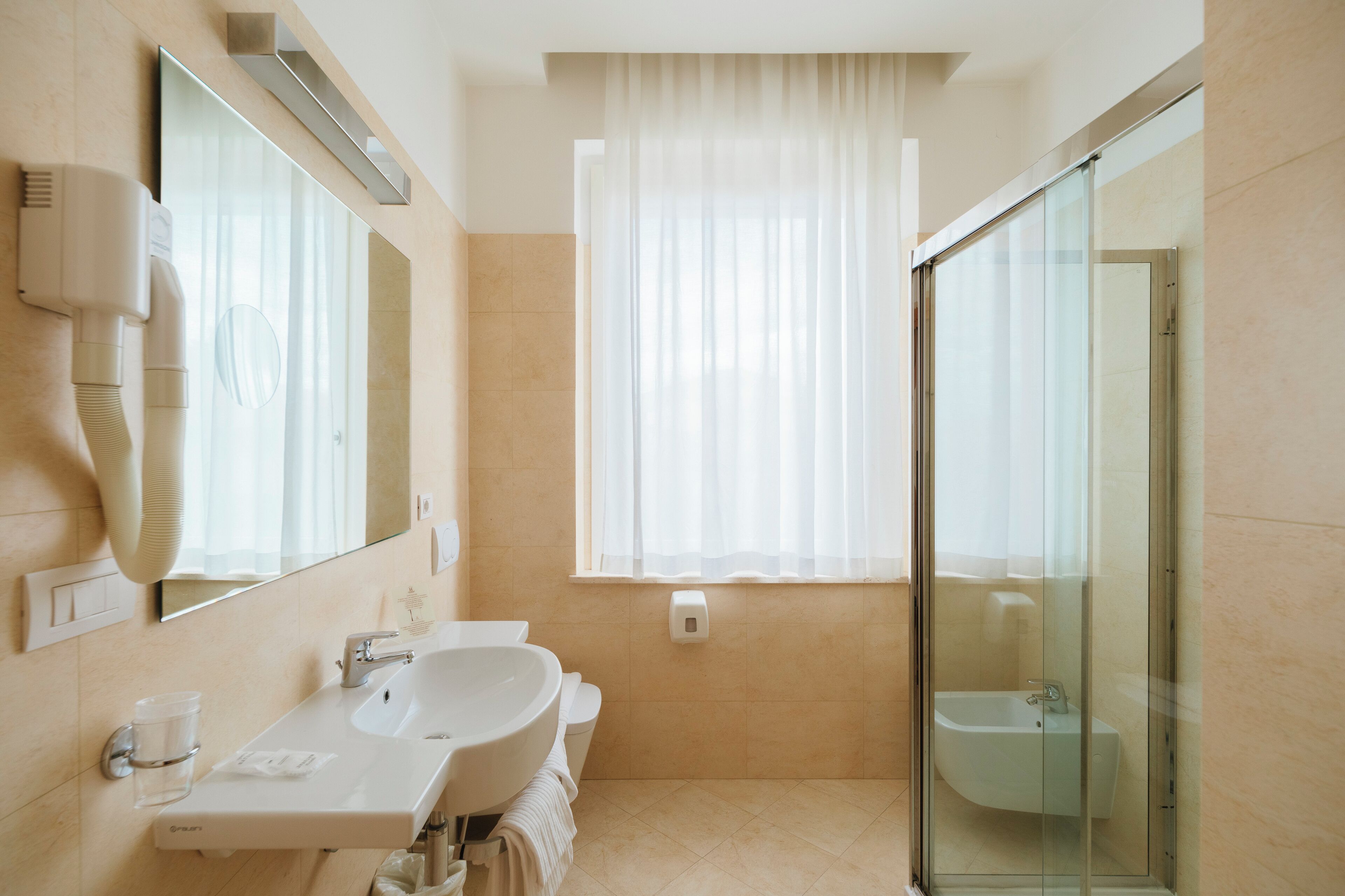 A modern bathroom with a large mirror, a sink, a toilet, and a glass-enclosed shower.