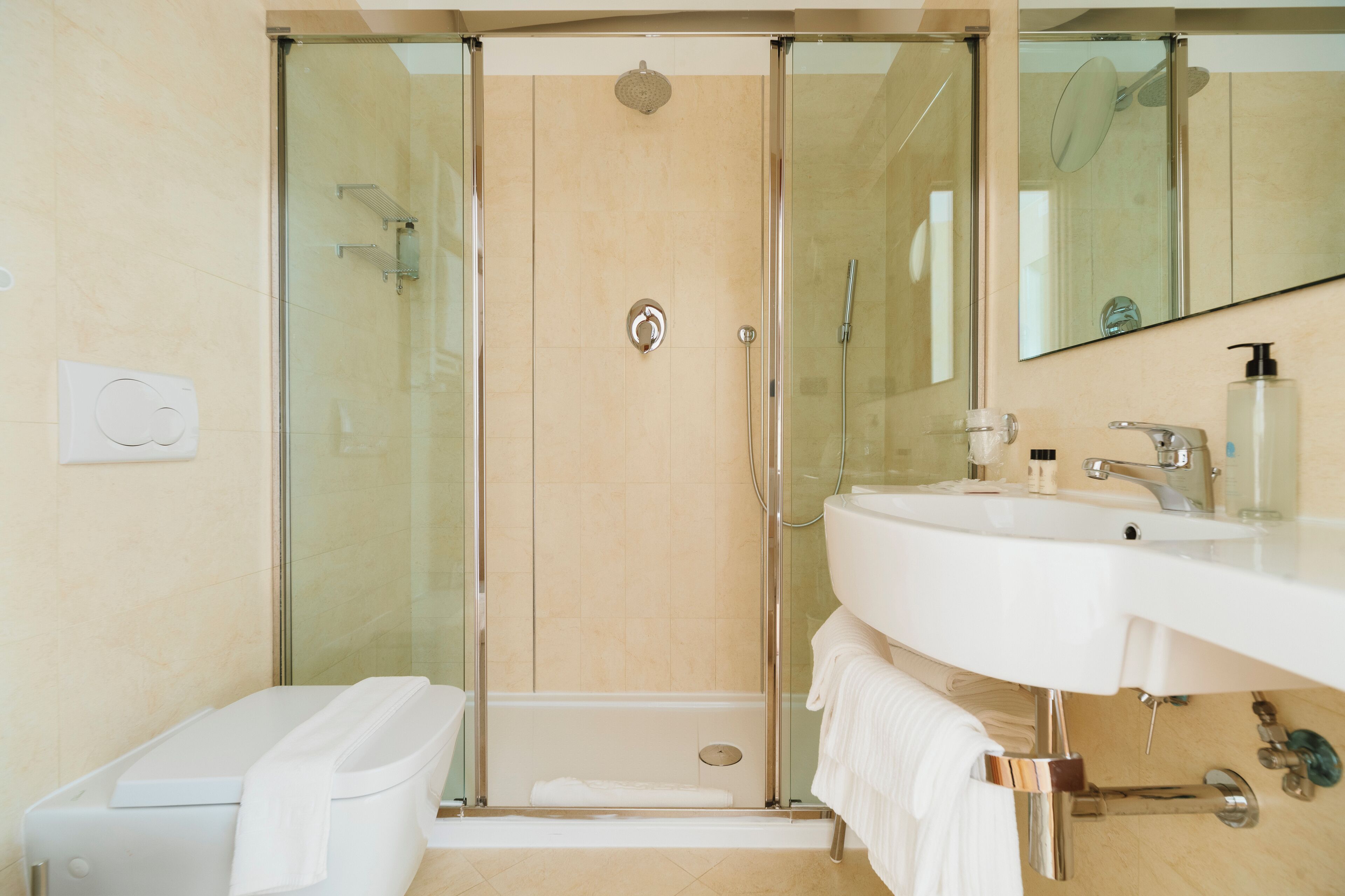 Un baño moderno con ducha envuelta en vidrio, un lavabo blanco y un espejo grande.