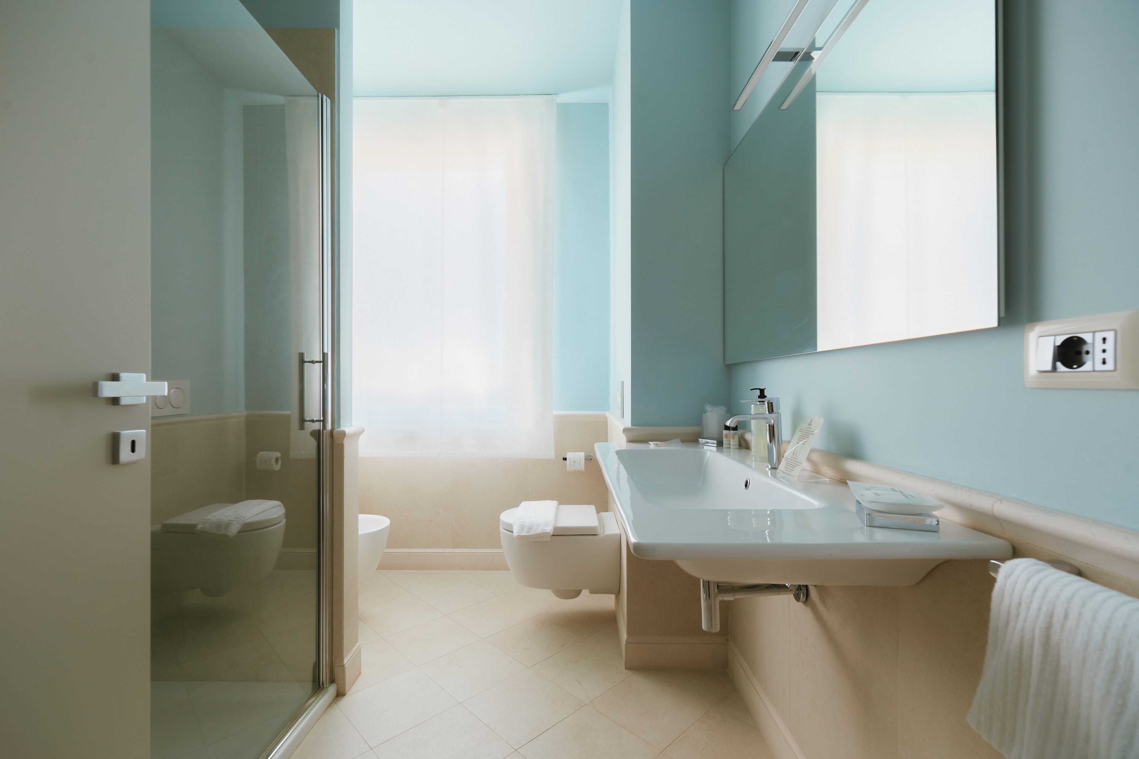 Ein modernes Badezimmer mit Duschkabine aus Glas, Toilette und Waschbecken mit Spiegel.
